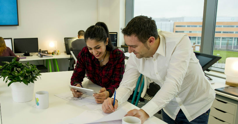 A student looks at a tablet while working alongside an employer during work experience.